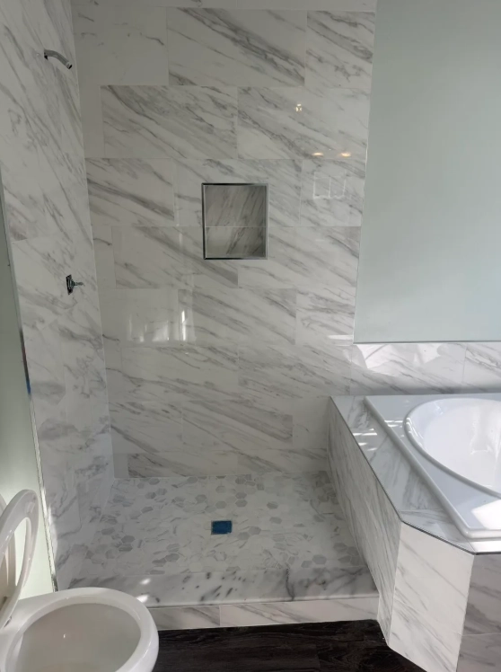 Calacatta marble shower with hexagon niche accent tile in Deerfield home