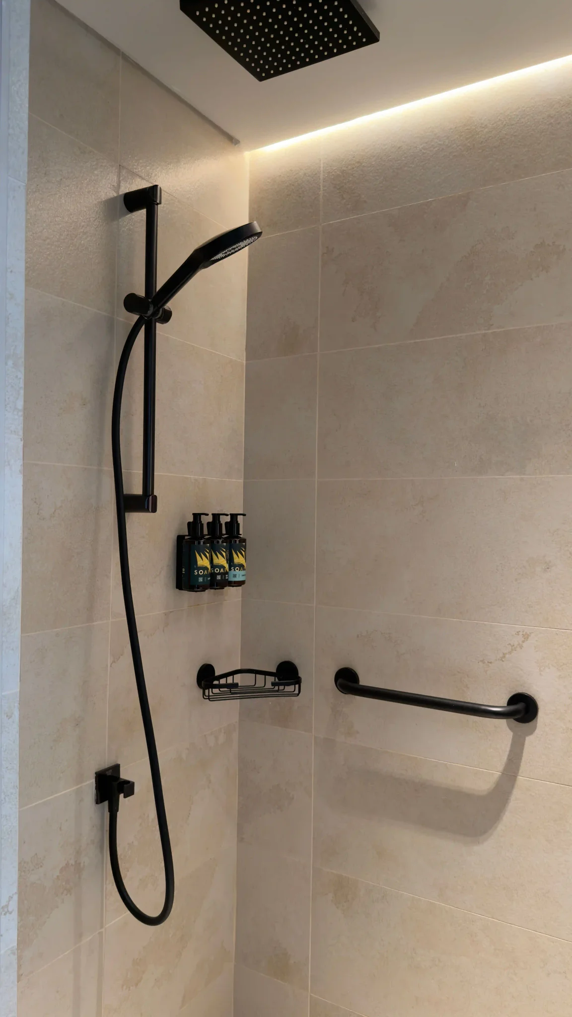 Luxury shower with matte black fixtures and large-format beige wall tile installed by Northbrook Tile Installer