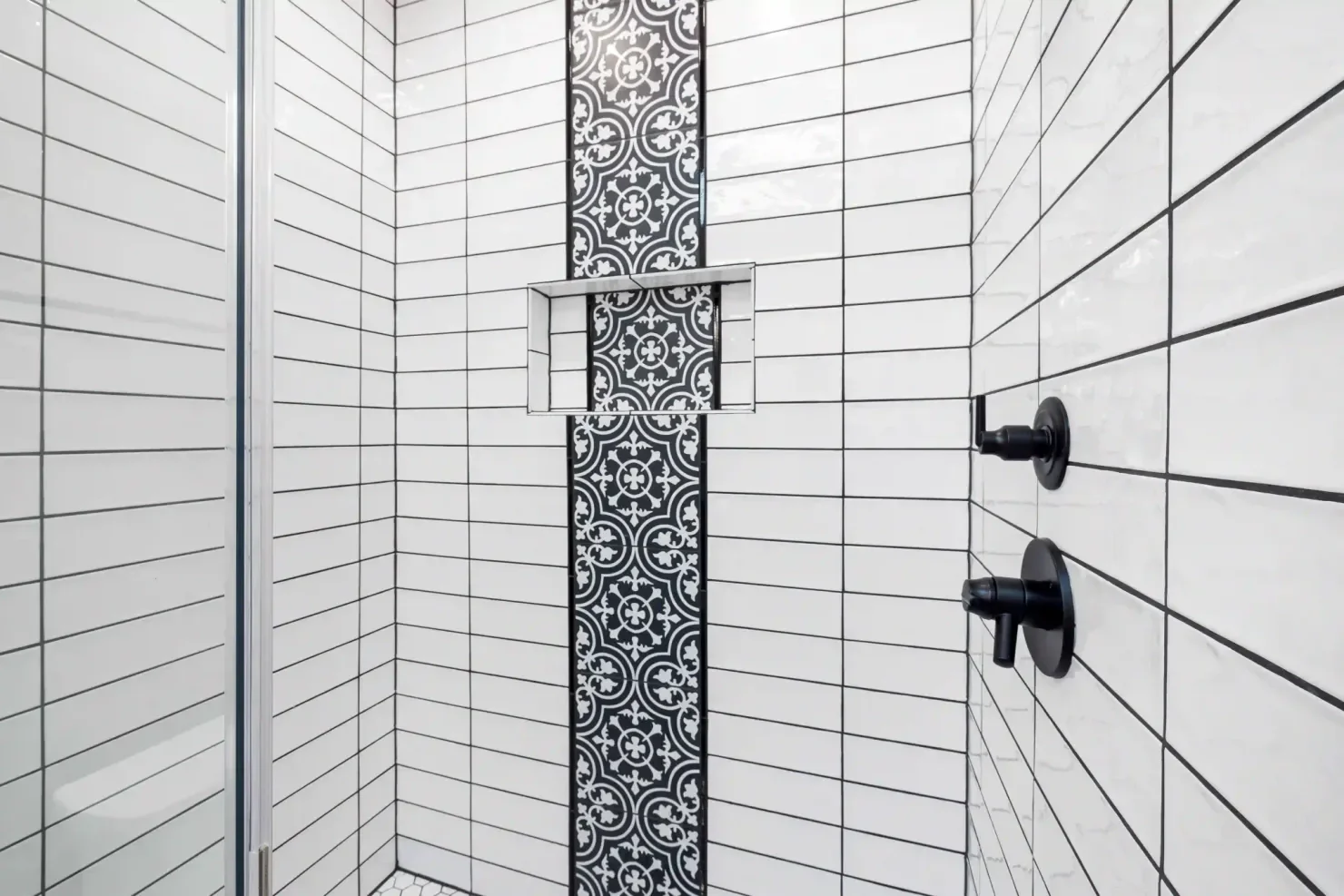 White subway tile shower with black ornamental accent strip, installed by Northbrook Tile Installer